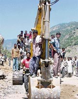 Bystanders look on as rescue workers search for survivors in the debris of a landslide at Kishtwar 