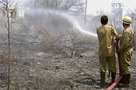 Firefighters busy dousing the flames in Narwal forest on the outskirts of Jammu city.