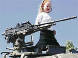 An Israeli girl walks on top of a Merkava tank during an Israeli army weapons exhibition in the Kiryat Arba settlement