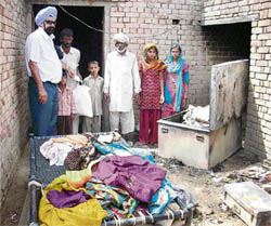 Resham Singh Bhangal, a Canada-based NRI, distributes financial aid and wheat flour to fire victims in Shehnal village in Fatehabad district on Friday.