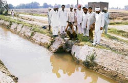 Panchayat members of Manna near the Badal village stand over the blockage that has been put by functionaries of the department to stop flow of waters towards the fields of Congress supporters