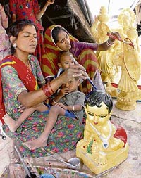 A child looks on as a mother gives the finishing touches to an idol in Karnal on the eve of Mothers Day on Saturday. 