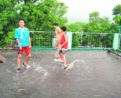 Children frolic in rain water accumulated on a terrace at Sundernagar after a downpour on Sunday. 