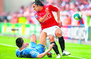 Manchester Uniteds Argentinian forward Carlos Tvez (R) is tackled by Wigan Athletic's Austrian midfielder Paul Scharner during their English Premier League match at the JJB Stadium in Wigan on Sunday. 
