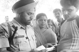 A policeman checks the voter ID of a villager;