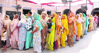 Women queue up at a polling booth in Baddowal village on Monday.