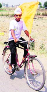 A boy, with a banner on his cycle, approaches a booth at Kalakh village near Ahmedgarh