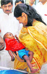 DMK MP Kanimozhi takes a malnutrition-affected child in her lap as BJP MP Shahnawaz Hussain looks on during their visit to the UNICEF-founded Nutritional Rehabilitation Centre at Saraiya in Muzaffarpur on Monday.