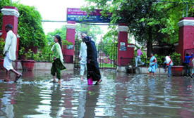 People wade through waterlogged road in front of LNJP Hospital. A sudden thunderstorm and rains caused waterlogging in many parts of the Capital on Wednesday. 