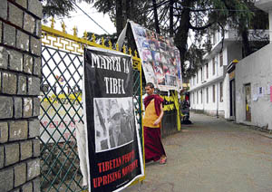 A Tibetan cleric walks past an anti-China banner strung outside the Dalai Lamas palace in Dharamsala in protest against the Chinese crackdown in Tibet. 