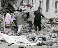 Rescuers carrying a survivor walk past a corpse on a street at the earthquake-hit Beichuan County in China on Tuesday. 