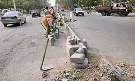 Workers place concrete blocks to close the small rotary of Sectors 19 and 20 in Chandigarh on Thursday.