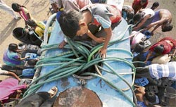 People crowd around a water tanker to fill their buckets and pots on a hot day in Ahmedabad