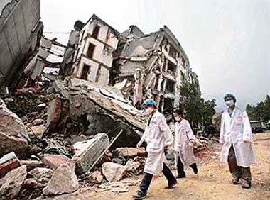 Medical personal walk past a damaged building in the city of Beichuan, located around 150 km north of Chengdu, in Sichuan Province on Friday.