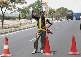 A worker diverts vehicular traffic using the Congress flag on the NH-! in Karnal