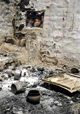 Children peep through the window of a house, which was gutted in fire, at Upper Beli Charana in Jammu on Sunday.