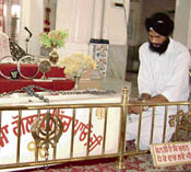 A Sikh devotee chains the gurdwara golak.