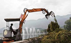 Weeds are unloaded from a machine after they are removed from the polluted Dal Lake in Srinagar