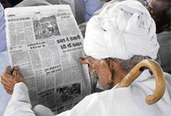 An elderly person reads a newspaper at a rally organised on the last day for canvassing in the Indri constituency