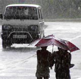 Pedestrians save themselves from the rain under an umbrella in Gurgaon