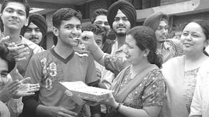 Patiala topper of CBSE Class XII Dheeraj Gakhar being offered sweets by his teacher in Patiala on Wednesday.