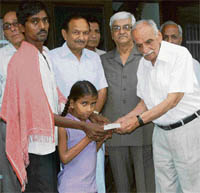 Members of the DR Vasudeva Charitable Trust present a demand draft of Rs 90,000 to Jamuna for her treatment.