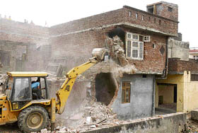 A bulldozer is busy demolishing illegal encroachments over the irrigation department land in Naibasti locality of Jammu on Thursday.