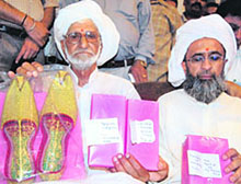 Dr Manmohan Singhs childhood friend Raja Mohammed Ali (left), accompanied by his relative Mehmood Ahmed, shows the jootis and other gifts he has brought from Pakistan, on his arrival in Amritsar on Friday.