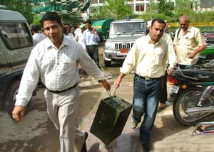 Election staff carry a ballot box to a polling booth in Muktsar on Sunday.