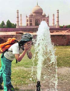 A tourist cools herself from a fountain to beat the heat near Taj Mahal in Agra