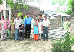 Residents along with pipes lying alongside the Saili road following suspension of the work on water supply line in Pathankot. 