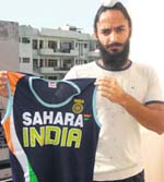 Indian hockey forward Rajpal Singh shows his T-shirt which he has donated to the organisers of Dharam Singh Memorial Hockey Tournament. 