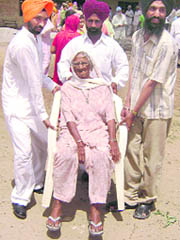 Supporters of candidates carry an old woman on chair at a Chhappar village near Ahmedgarh on Monday.