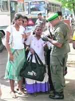 A soldier checks the identification cards of bus passengers at a checkpoint leading to the city in Colombo on Monday. Sri Lanka intensified its vigilance on public transport after two bombs were found on two passenger buses over the weekend.