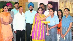 Jasleen Bhullar, topper, being offered sweet at Tagore International School at Sahnewal on Thursday.