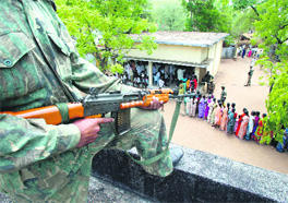 A CRPF personnel stands guard as villagers wait to cast their votes in Peddekodepaka village, 230 km from Hyderabad, on Thursday.