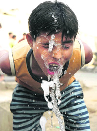 As temperature goes up, a boy quenches his thirst from a leaked water pipe in Jammu. 