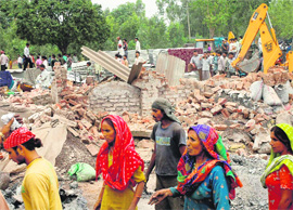 Workers try to salvage their belongings after a demolition drive against warehouses in Daria village, Chandigarh, on Monday. 