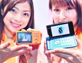 Employees of Japan's mobile operator KDDI display a new mobile phone lineup "Sportio" (L) of Toshiba and "W62H" (R) of Hitachi in Tokyo