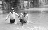 School boys wade through water under the bridge after heavy rain at Ambala Cantonment on Thursday.
