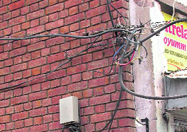 Electricity and telephone wires intermingle with each other on the wall of a showroom in the Sector 26 market. A tragedy is waiting to happen.