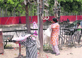 2 Wires from a high-voltage transformer hang precariously at Sector 26, Grain Market, frequented by millions everyday. The wire misses this womans head by a whisker.
