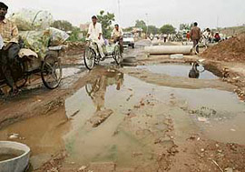 Road users negotiate trenches, filled with rainwater, on the road along the elevated Chandigarh-Ludhiana railway track, linking Chandigarh with Phase XI, Mohali.