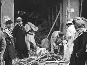 Armed Pakistani tribesmen gather at a destroyed music shop after a blast in Miranshah in the tribal-ruled Taliban stronghold of North Waziristan
