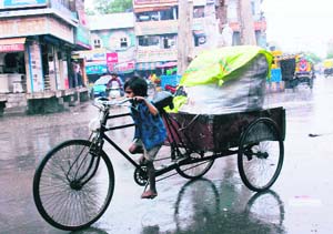 A child pulls a loaded rehri during rain in Karnal on World Day against Child Labour on Thursday. 