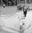 An old man crosses the road carrying his granddaughter outside Government Rajindra Hospital following heavy rains in Patiala.