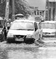 Vehicles pass through a waterlogged street after heavy rain lashed Ambala city