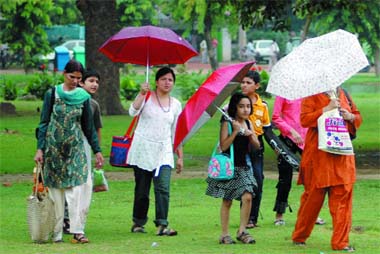 A family enjoys the rain at the India Gate in New Delhi on Friday. The rain brought relief from the sultry heat. Tribune photo: Mukesh Aggarwal