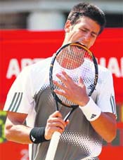 FIGHT FOR THE BITE: Serbias Novak Djokovic (L) bites his racquet after losing a point against Spains Rafael Nadal in the final of the Queens Club tournament in London