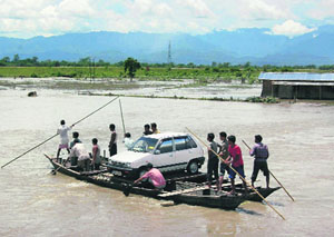 People transport a car on the Hingora river in Lakhimpur district, about 400 km east of Guwahati, on Monday.